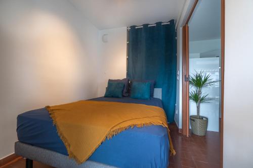 ein Schlafzimmer mit einem blauen Bett und einer gelben Decke in der Unterkunft Appartement à quelques pas de la mer WIFI CLIM PARKING in La Grande-Motte