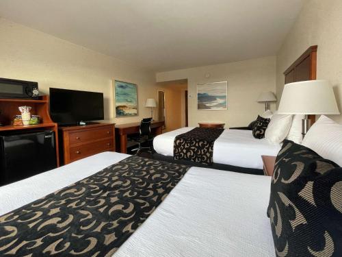 a hotel room with two beds and a flat screen tv at Best Western Plus Waterville Grand Hotel in Waterville
