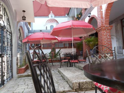 a patio with tables and chairs with red umbrellas at Hotel Boutique TEKALI INN in Cuetzalán del Progreso