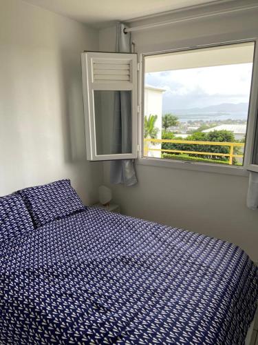 a bedroom with a bed and a window at F2 Lamentin in Le Lamentin