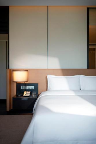 a bedroom with a bed and a nightstand with a phone at New World Shenyang Hotel in Shenyang