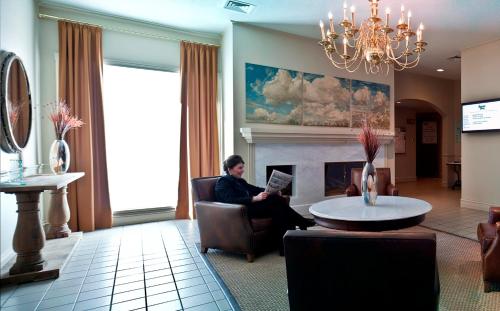a man sitting in a chair in a living room at Atlantic Host Hotel, Trademark Collection by Wyndham in Bathurst