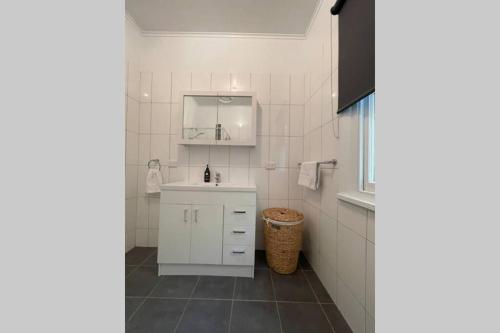 a white bathroom with a sink and a mirror at Hazeldene - The Best Location In Town! in Myrtleford