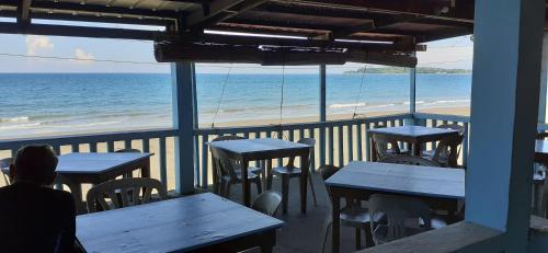 Bella's Beach Resort Apartment 8 في باوانج: شخص يجلس على الطاولات في مطعم مطل على الشاطئ