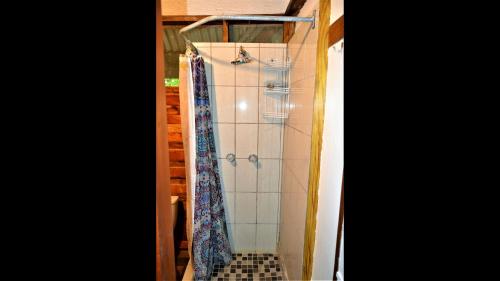 cabina de ducha con corbatas colgadas en la pared en Hummingbird Rest a fully equipped cabana in subtropic garden, en San Ignacio