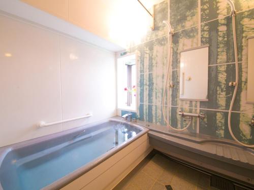 un bagno con ampia vasca e finestra di ホテル盛松館 a Shizuoka