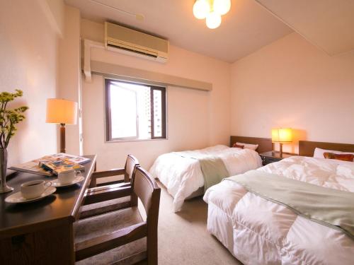 Habitación de hotel con 2 camas, mesa y escritorio en ホテル盛松館 en Shizuoka