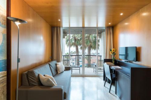 a living room with a couch and a desk with a television at Estela Barcelona in Sitges