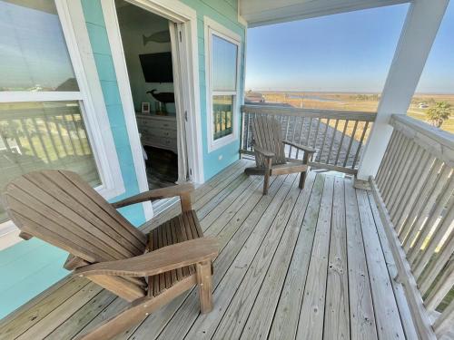 a rocking chair on a porch with a view of the ocean at #Latitude Adjustment Home in Bolivar Peninsula