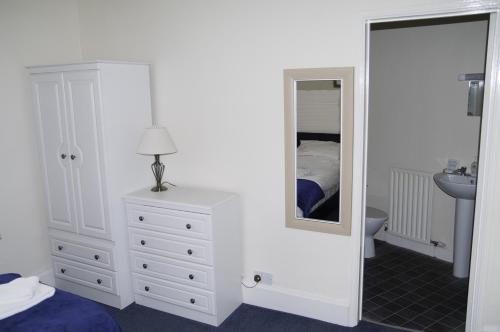 a bedroom with a white dresser and a mirror at Fourways Guest House in Thirsk