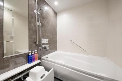 a bathroom with a white tub and a shower at Richmond Hotel Morioka Ekimae in Morioka