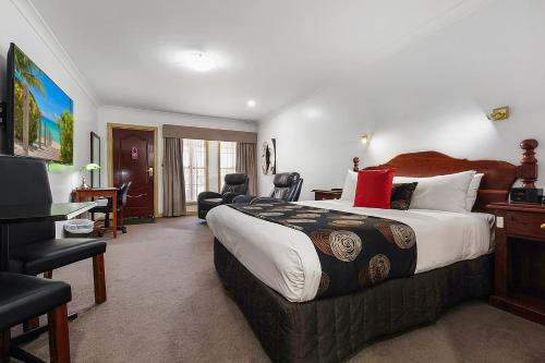 um quarto de hotel com uma cama grande e uma secretária em Georgian Motor Lodge em Echuca
