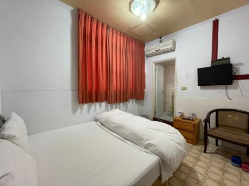 a bedroom with a white bed and a red curtain at Da Fang Hotel in Jiaoxi