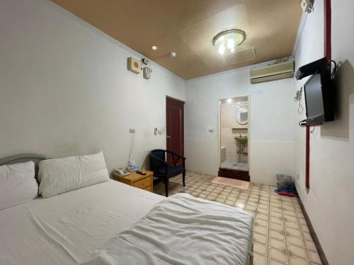 a bedroom with a white bed and a bathroom at Da Fang Hotel in Jiaoxi