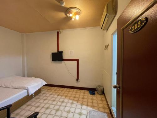 a room with a bed and a tv on the wall at Da Fang Hotel in Jiaoxi
