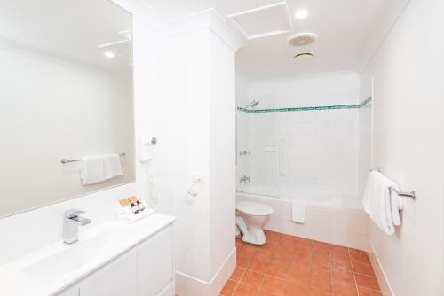a white bathroom with a toilet and a sink at The Brighton Apartments in Toronto