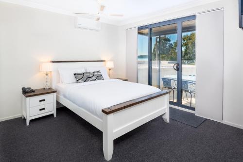 a white bedroom with a bed and a window at The Brighton Apartments in Toronto