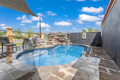 a swimming pool in a yard with chairs and a fence at Georgian Motor Lodge in Echuca