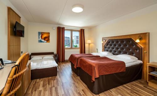 a hotel room with two beds and a television at Hotel Vallonia in Vaasa