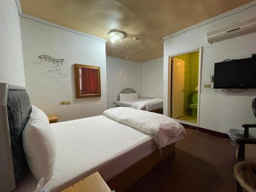 a bedroom with a large white bed and a tv at Da Fang Hotel in Jiaoxi