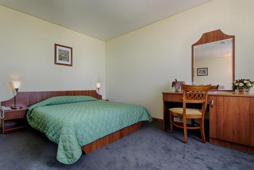 a bedroom with a bed and a desk and a mirror at Hemus Hotel Sofia in Sofia