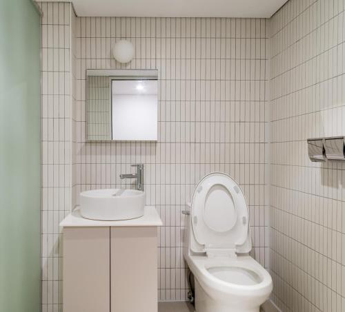 uma casa de banho com um WC branco e um lavatório. em Upflo Hostel em Seul