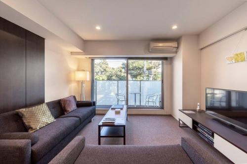 a living room with a couch and a tv at Pangoo Shinagawa in Tokyo