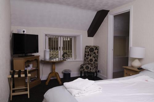 a bedroom with a bed and a tv and a chair at Fourways Guest House in Thirsk
