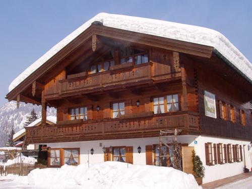 a large wooden building with snow on top of it at Gästehaus Schwarzlofer in Reit im Winkl