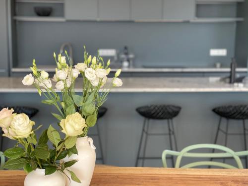 un vase blanc avec des fleurs sur une table dans l'établissement Villa EVA, vue mer et montagne, plage à pieds, à Sainte-Lucie de Porto-Vecchio