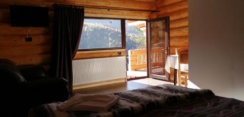 1 dormitorio con una gran ventana en una cabaña de madera en Cabanele silvania 1, en Statjunea Borsa