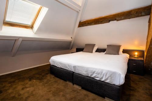 a bedroom with a large white bed with a window at Landgoed Kasteel de Hoogenweerth in Maastricht