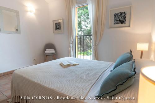 a bedroom with a bed with blue pillows and a window at CYRNOS in Porto-Vecchio