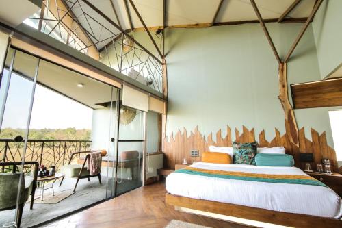 a bedroom with a large bed and a balcony at Tadoba Jungle Camp in Mohurli