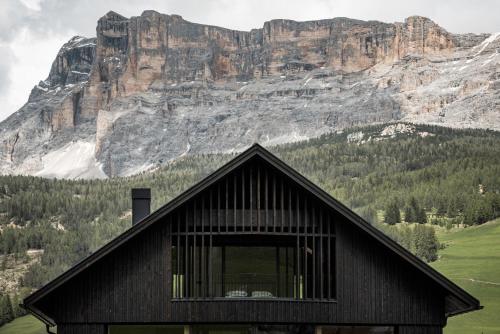 a black building with a mountain in the background at Larix Lodge in La Villa