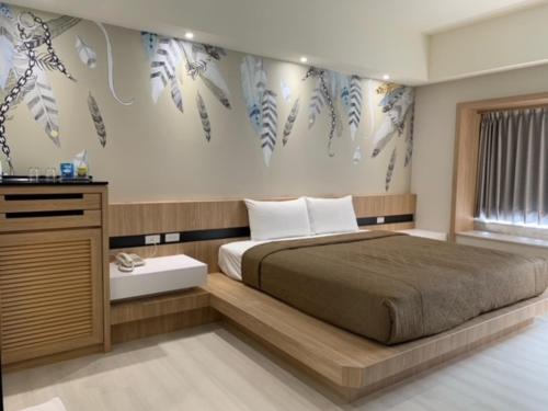 1 dormitorio con cama y pared con plumas en YHC Hotel, en Tainan