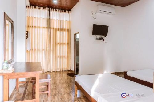 a room with a bed and a table and a tv at The Grand Pearl Resort in Monaragala