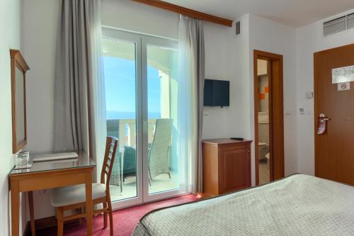 a hotel room with a bed and a desk and a window at Hotel Villa Dvor in Omiš
