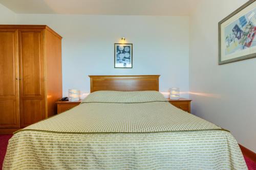 a bedroom with a bed and a wooden cabinet at Hotel Villa Dvor in Omiš