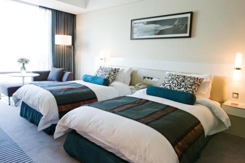 a hotel room with two beds and a couch at Ramada Plaza by Wyndham Suwon in Suwon