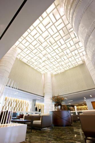 a lobby with a large ceiling and chairs and tables at Ramada Plaza by Wyndham Suwon in Suwon