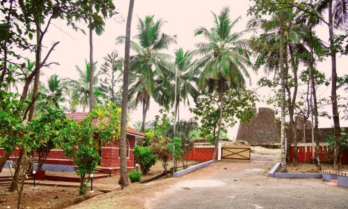 a courtyard with palm trees and a red fence at ShriGo Bekal Fort Resort & Spa in Bekal