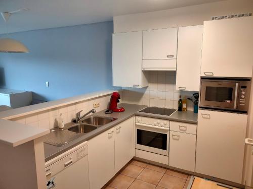 a kitchen with white cabinets and a sink at Zongericht appartement met zicht op de jachthaven in Ostend