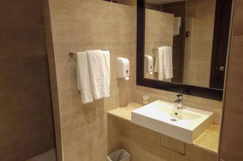 een badkamer met een wastafel, een spiegel en handdoeken bij Fiesta Beach Djerba in Midoun
