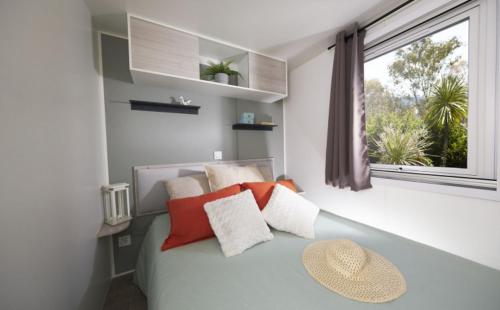 a bedroom with a bed with pillows and a window at Camping le Mas Fleuri in Sospel