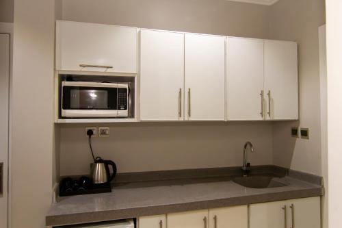 a kitchen with white cabinets and a microwave at ال متعب سويتس الفلاح 3 in Riyadh