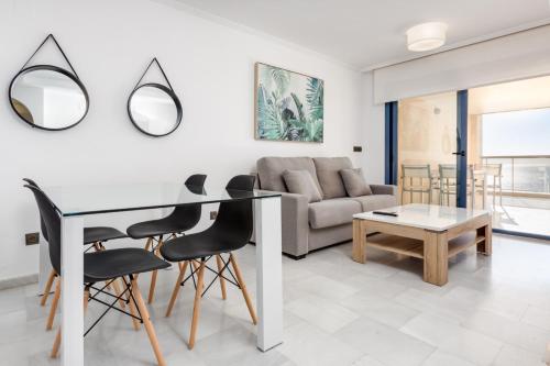 ein Wohnzimmer mit einem Tisch, Stühlen und einem Sofa in der Unterkunft 1st Line Mascarat Beach - Solarium Terrace & Pool in Altea