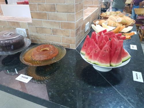 a table topped with a bowl of watermelon and a donut at Hotel Araçás in Carolina