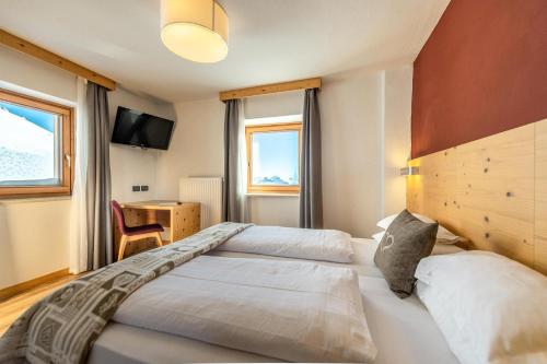 una camera d'albergo con due letti e una televisione di Hotel Col di Lana a Canazei