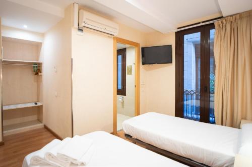 a hotel room with two beds and a tv at Hostal Fina in Barcelona